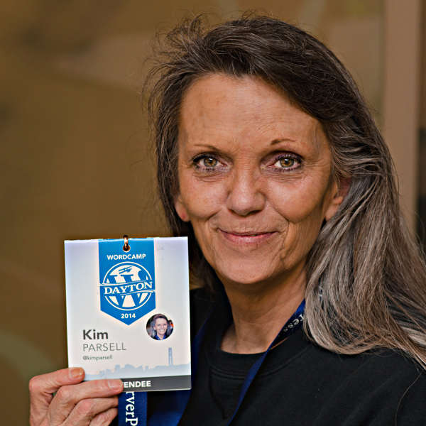 Kim Parsell holding up her WordCamp Dayton badge