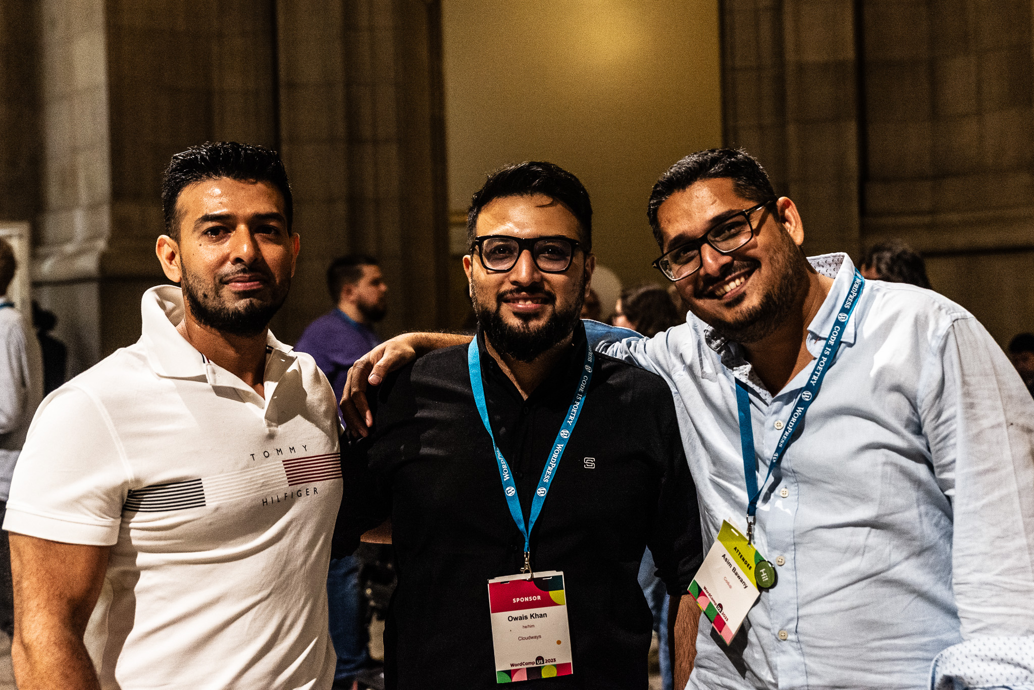 Three attendees smile for the camera at an after-hours event.