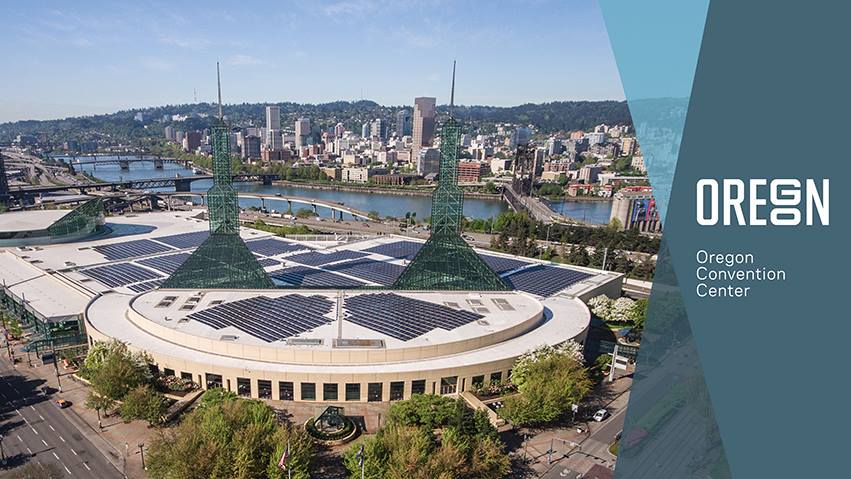 Aerial photo of the convention center, with the river and city skyline in the background.